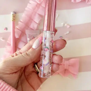 A pink and white wand-shaped lip gloss applicator with sparkles and a pink bow accent.