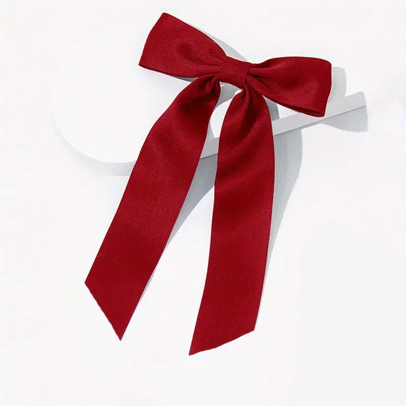 A large red velvet bow hair clip with a wide, flowing design.