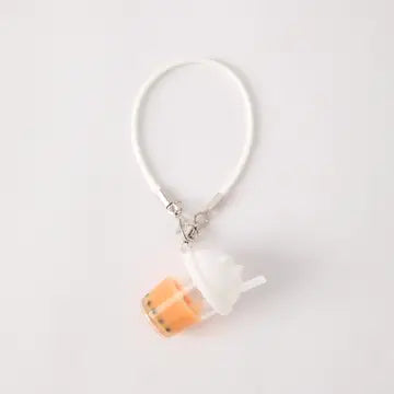A white, silicone strap bracelet with a clear plastic cube charm filled with orange powder or crystals.