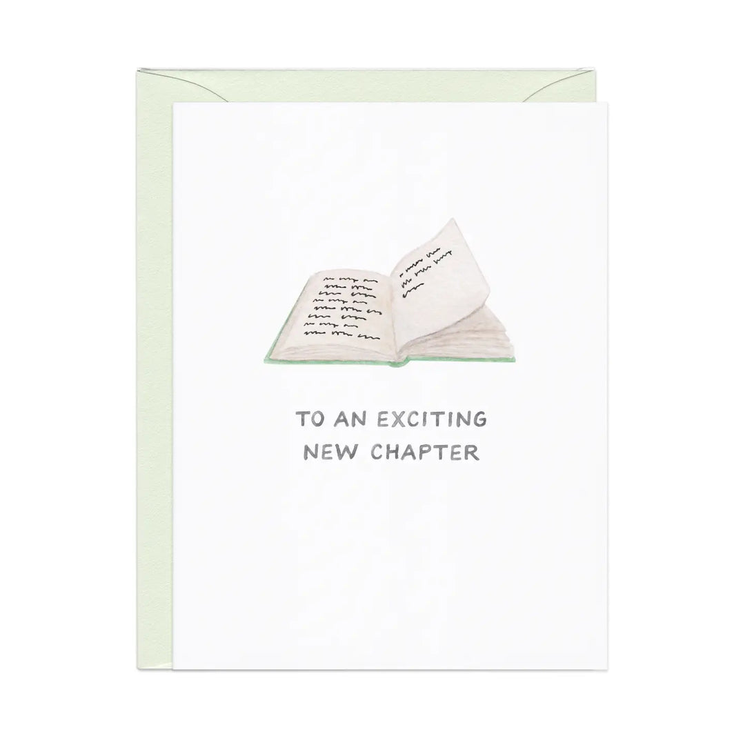 White greeting card with a simple illustration of an open book and text reading "TO AN EXCITING NEW CHAPTER".