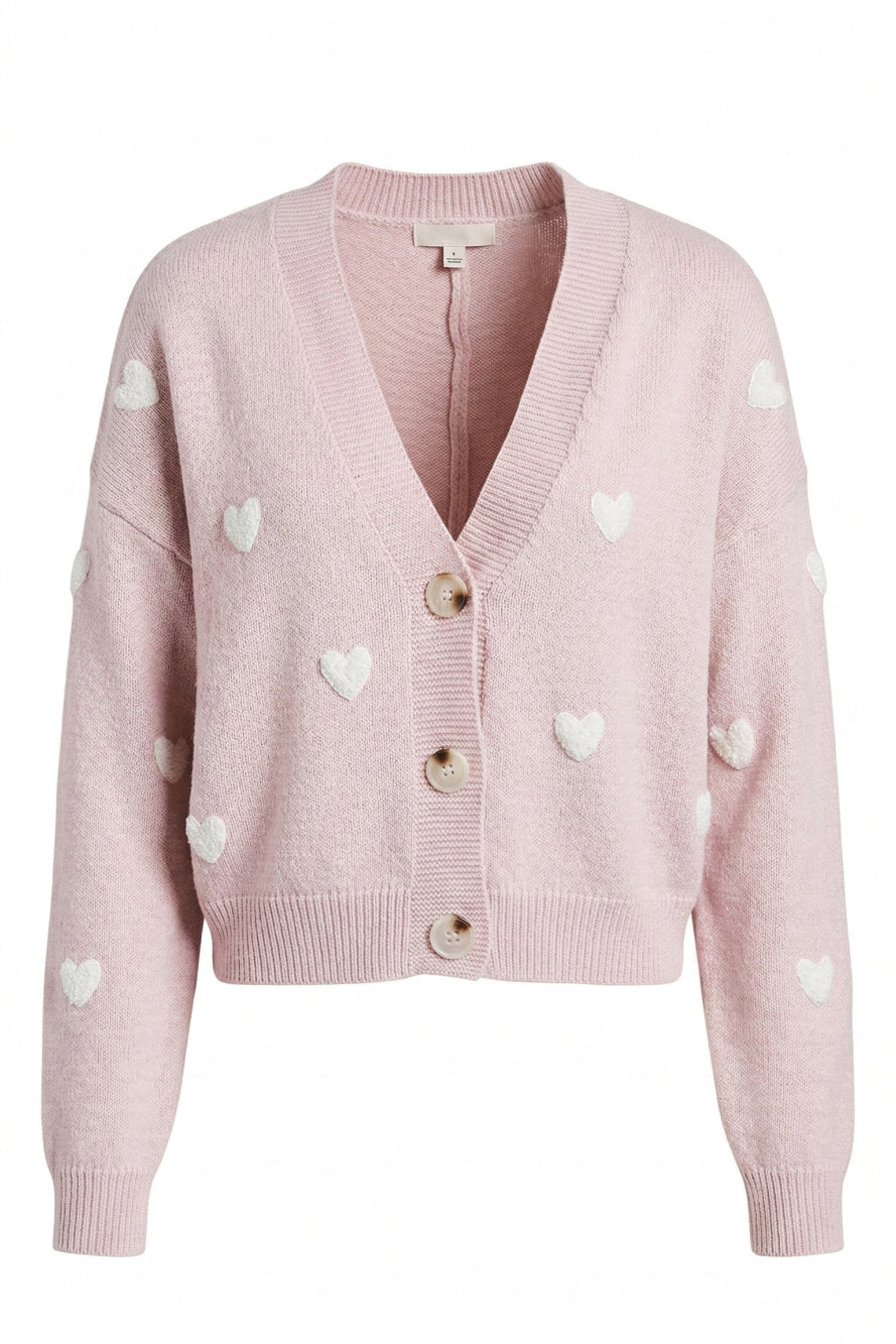A pink knit cardigan with white heart-shaped patterns, featuring a V-neck, button front closure, and ribbed trim.