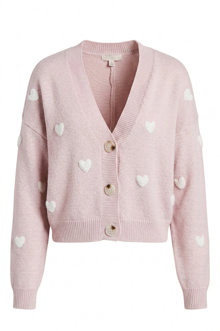 A pink knit cardigan with white heart-shaped patterns, featuring a V-neck, button front closure, and ribbed trim.