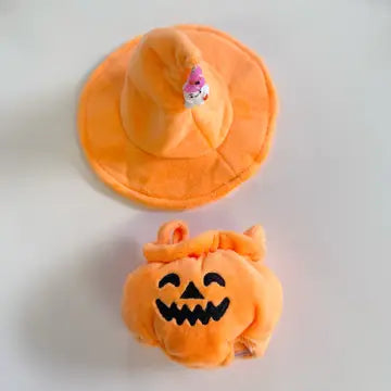 Orange plush pumpkin bucket with jack-o-lantern face and matching orange sun hat with purple flower accent.