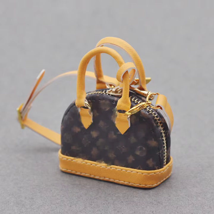 A small designer shoulder bag with a black and yellow patterned exterior, gold-toned hardware, and a structured, compact shape.