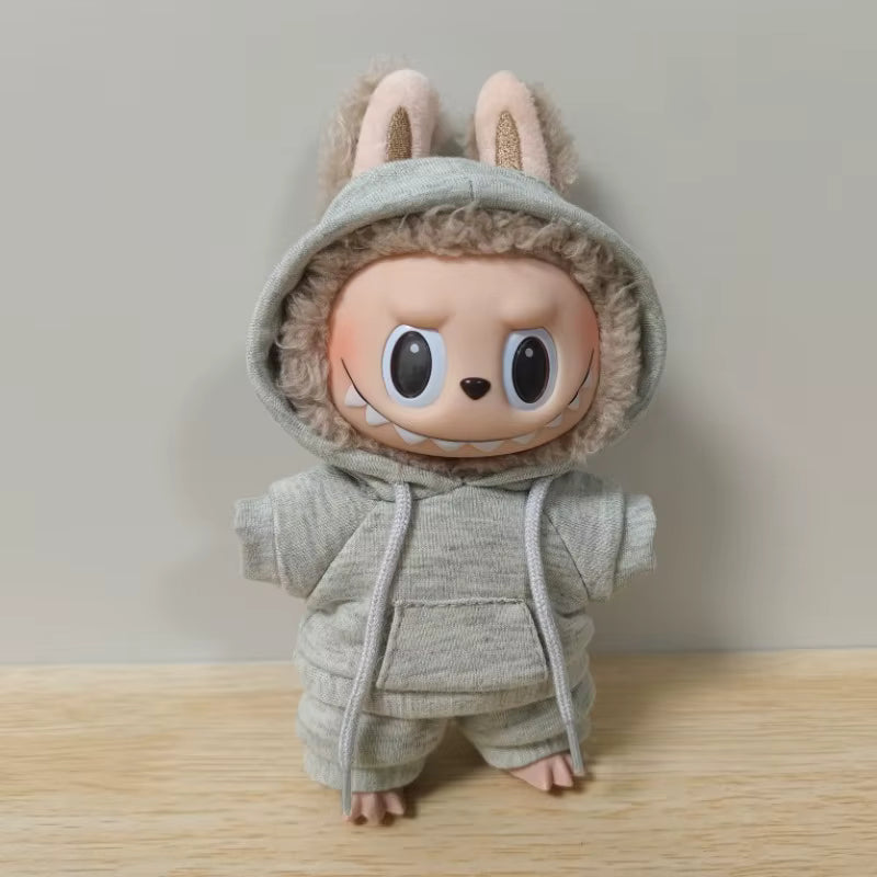A plush, gray stuffed animal in a hoodie and sweatsuit, with oversized eyes and ears resembling a sloth or other cute animal character.