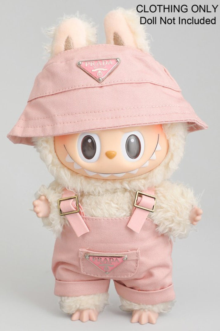 Plush pink toy wearing Prada-branded overall and matching bucket hat, with large eyes and furry white trim.