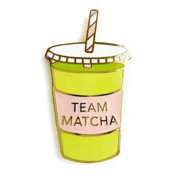Green enamel pin in the shape of a matcha tea drink with a straw, featuring the text "TEAM MATCHA" on a pink background.
