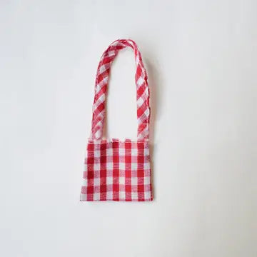 A red and white gingham plaid, handmade fabric bag with a braided strap handle.