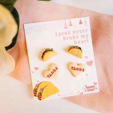 A colorful set of stud earrings with miniature food designs, including tacos and taco shells in various sizes and shapes, on a pink background.