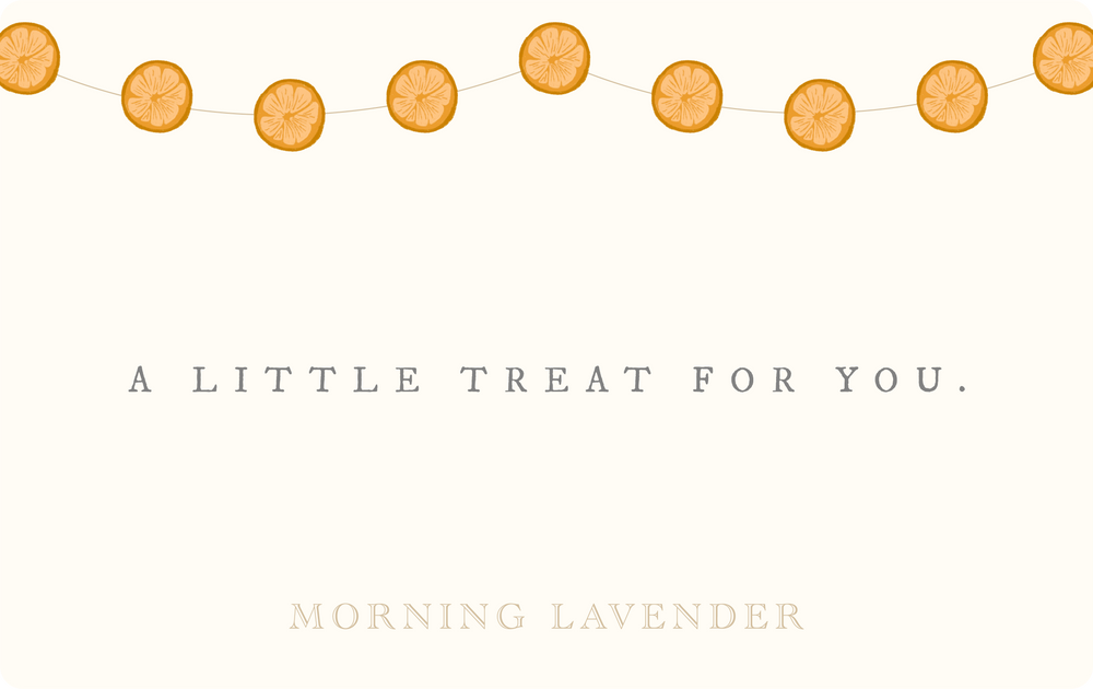 A string of orange citrus slices hanging against a cream background with the text "A little treat for you. Morning Lavender".