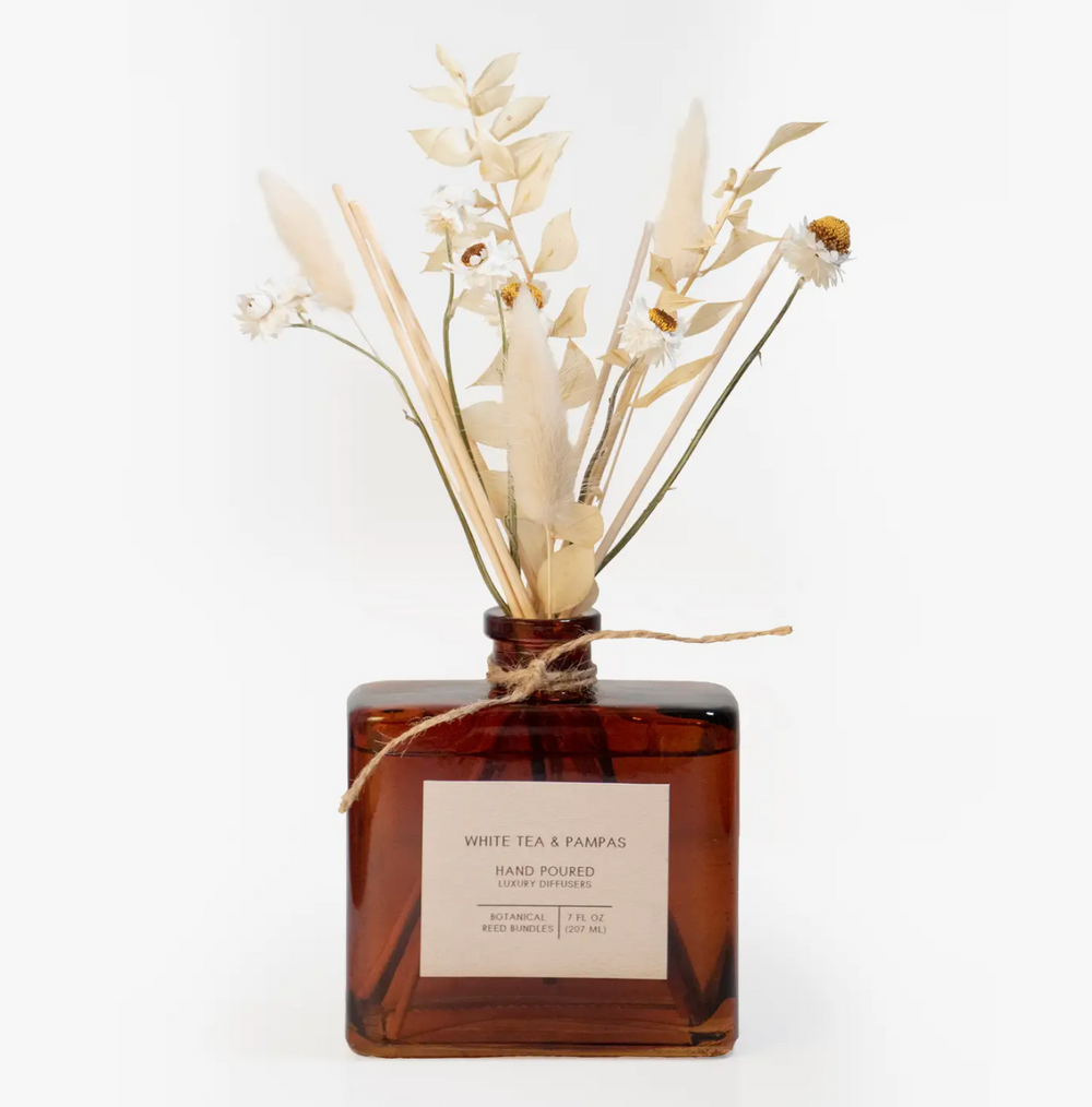 A glass bottle filled with a fragrant bouquet of white tea and pampas grass, tied with twine, creating an elegant and natural home diffuser.